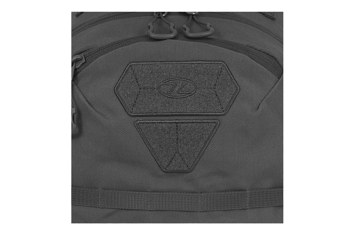 Nahaufnahme eines schwarzen taktischen Rucksacks mit einem gebrandeten Klettverschlussbereich für Moralaufnäher und robusten Reißverschlüssen.