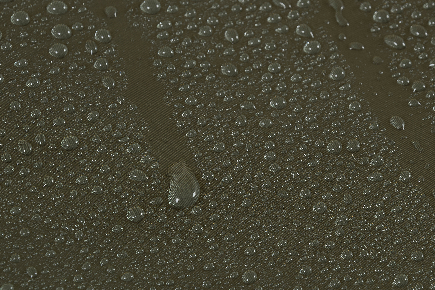 Nahaufnahme von Wassertropfen, die auf einer dunkelolivgrünen, wasserabweisenden Stoffoberfläche perlen und Textur und Details zeigen.