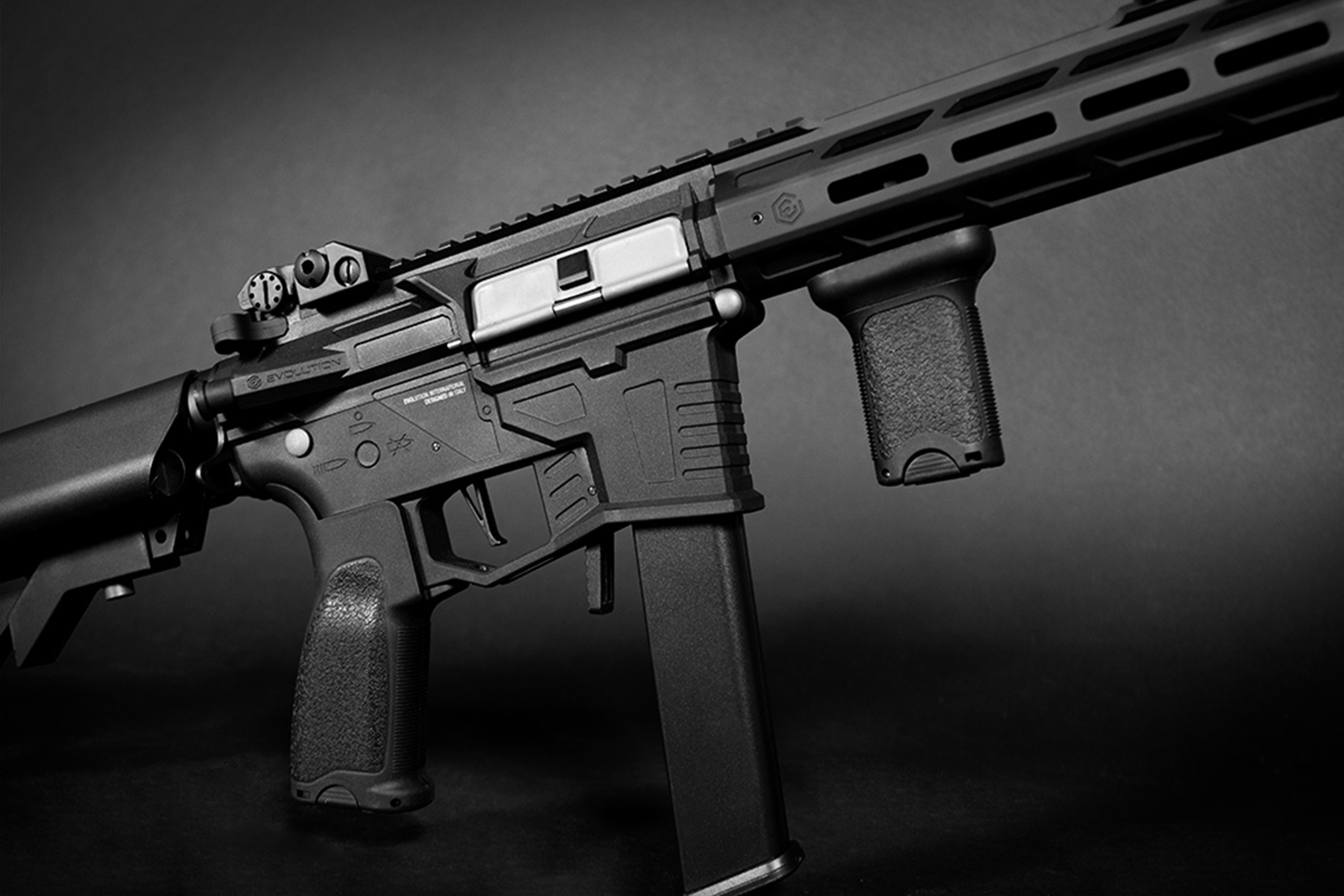 Black Evolution International Luftgewehr mit taktischem Handschutz, vertikalem Griff und Magazin auf dunklem Hintergrund.