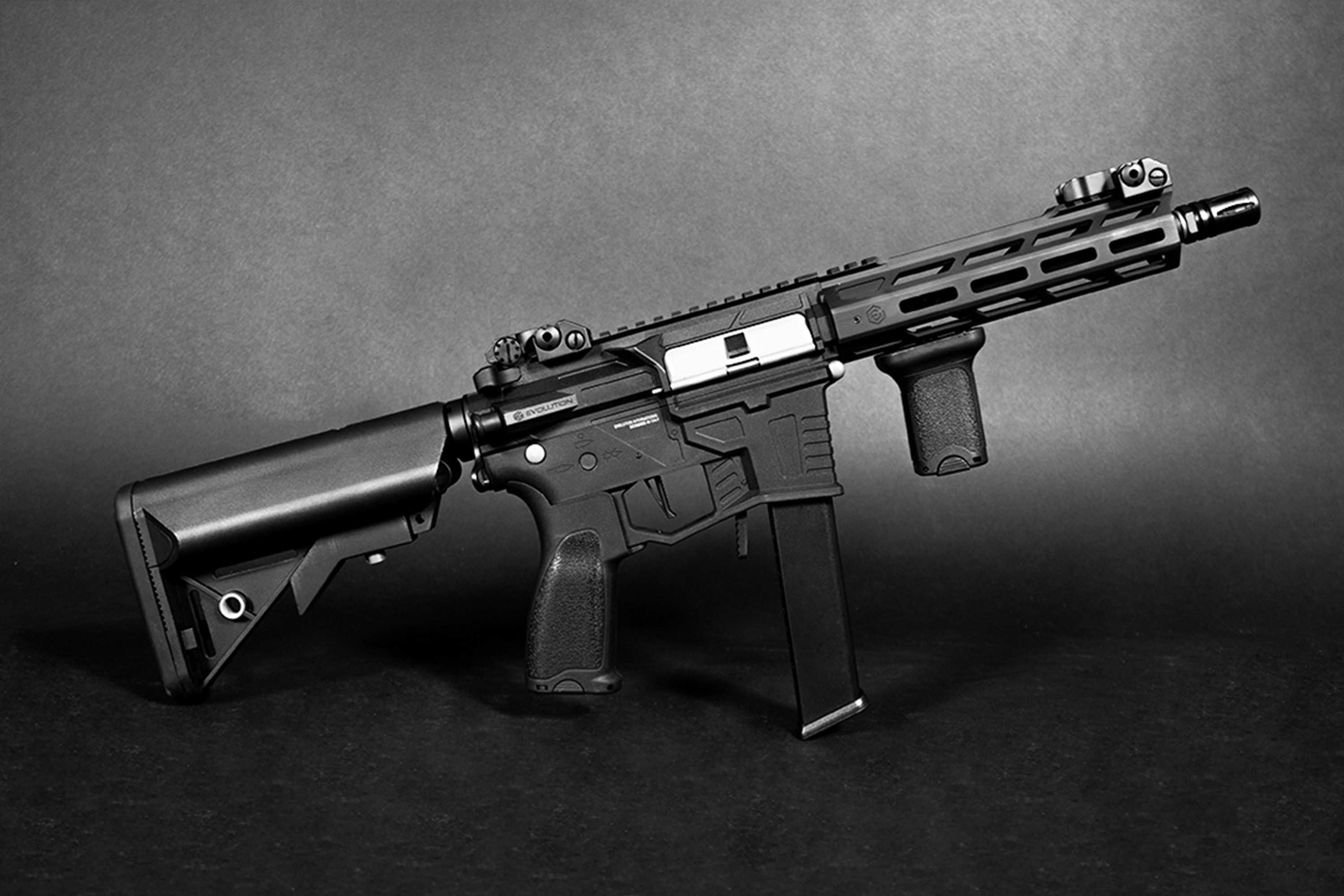 Schwarzes Evolution-Luftgewehr mit taktischem Handschutz, verstellbarem Schaft und vertikalem Griff auf dunklem Studiohintergrund.