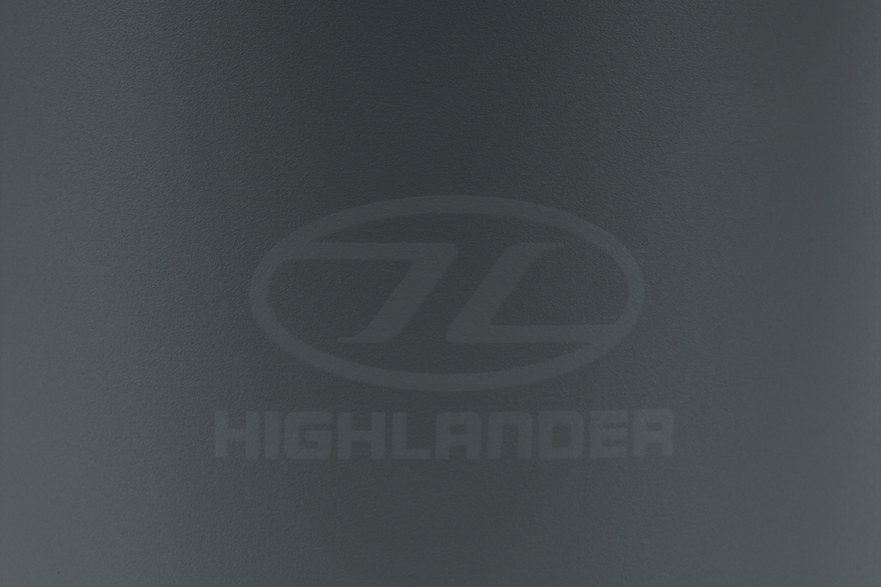Nahaufnahme einer matten dunkelgrauen Oberfläche mit dem geprägten Highlander-Markenlogo und Text in zentriertem Design.