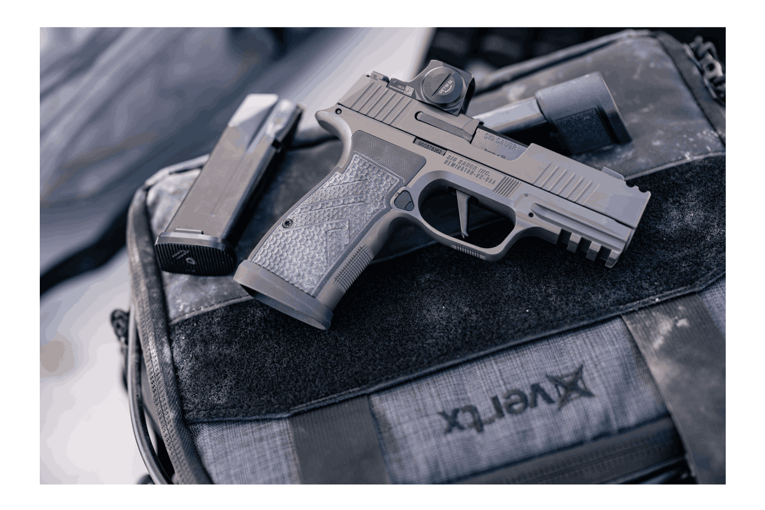 Graue Luftpistole mit strukturiertem Griff und Leuchtpunktvisier auf einer taktischen Tasche, ideal für Schießbegeisterte.