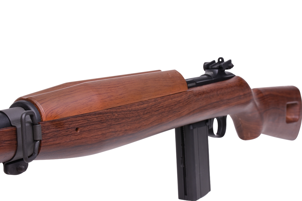 Nahaufnahme eines M1 Carbine-Luftgewehrs mit klassischem Holzschaft, schwarzem Metalllauf und Magazin auf weißem Hintergrund.