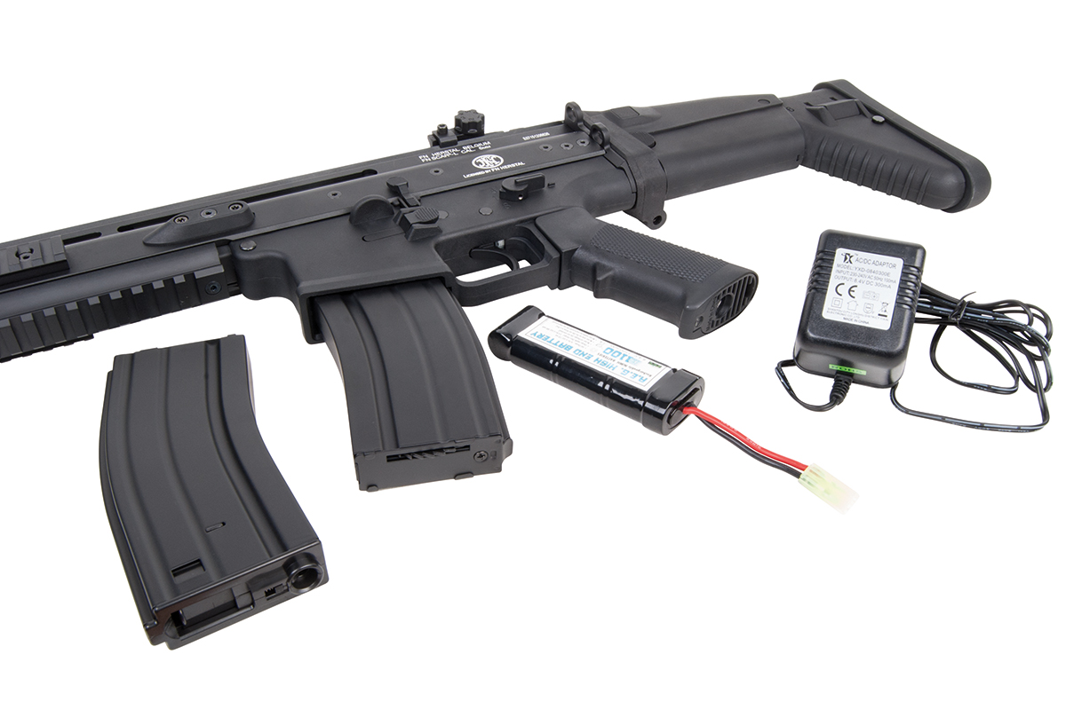 Schwarzes FN SCAR-L Airsoft-Gewehr mit Ersatzmagazin, wiederaufladbarem Akku und Netzteil auf weißem Hintergrund.