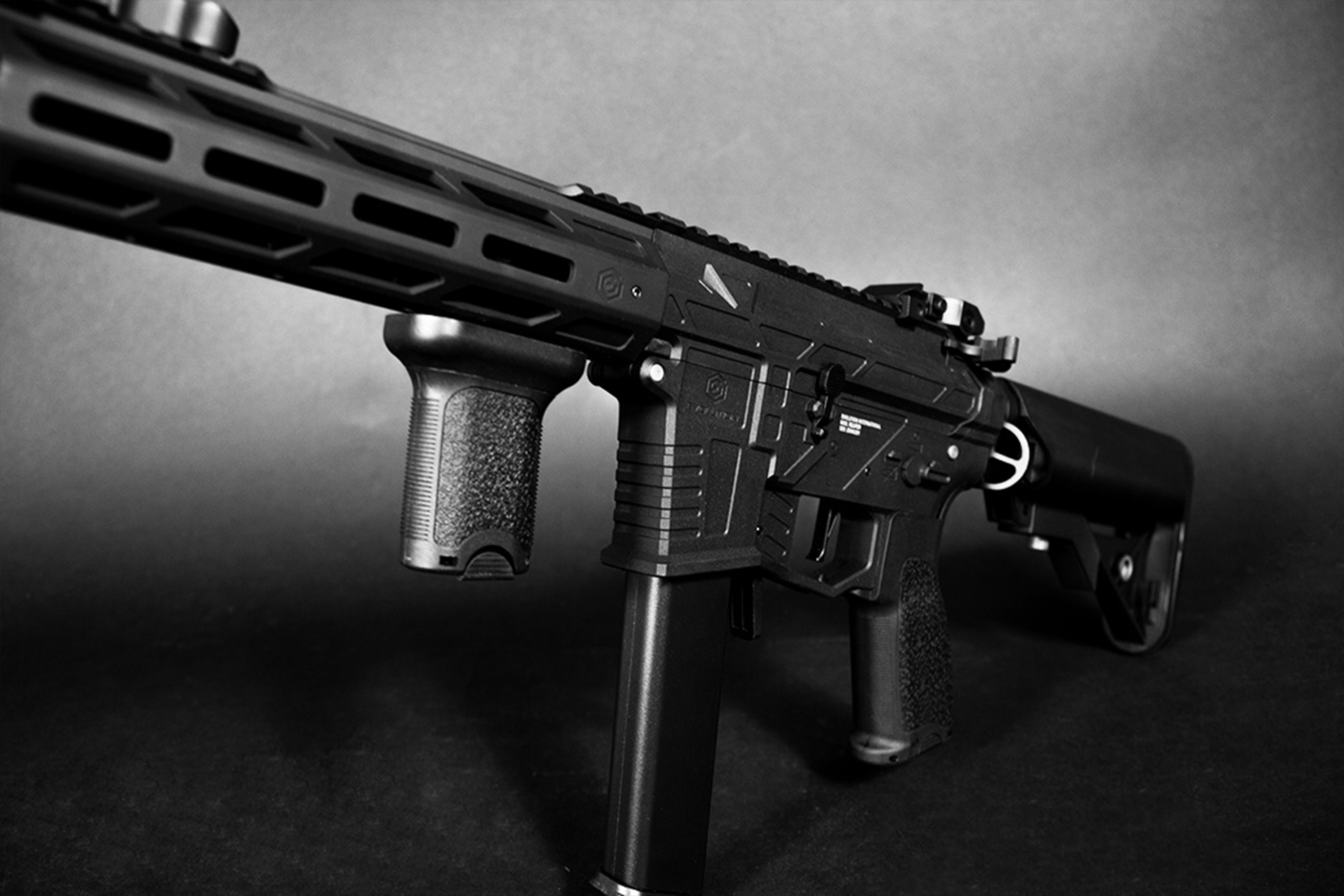 Schwarzes Airsoft-Gewehr mit taktischem Handschutz, vertikalem Griff und Magazin, präsentiert auf einem dunklen Studiohintergrund.