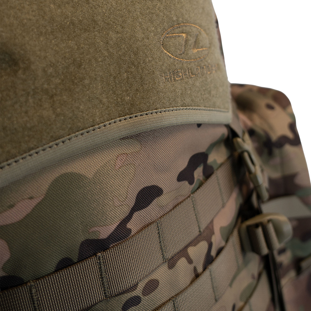 Nahaufnahme eines taktischen Rucksacks im Multicam-Tarnmuster mit olivgrünem Klettverschluss und Highlander-Logo auf weißem Hintergrund.
