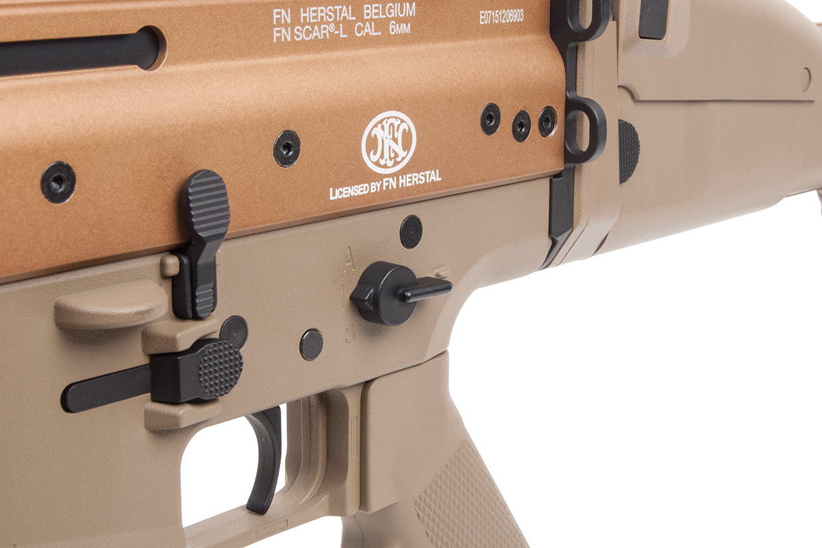Nahaufnahme des hellbraunen Airsoft-Gewehrempfängers FN Herstal SCAR-L mit offiziellen Markierungen und Feuerwahlschalter.