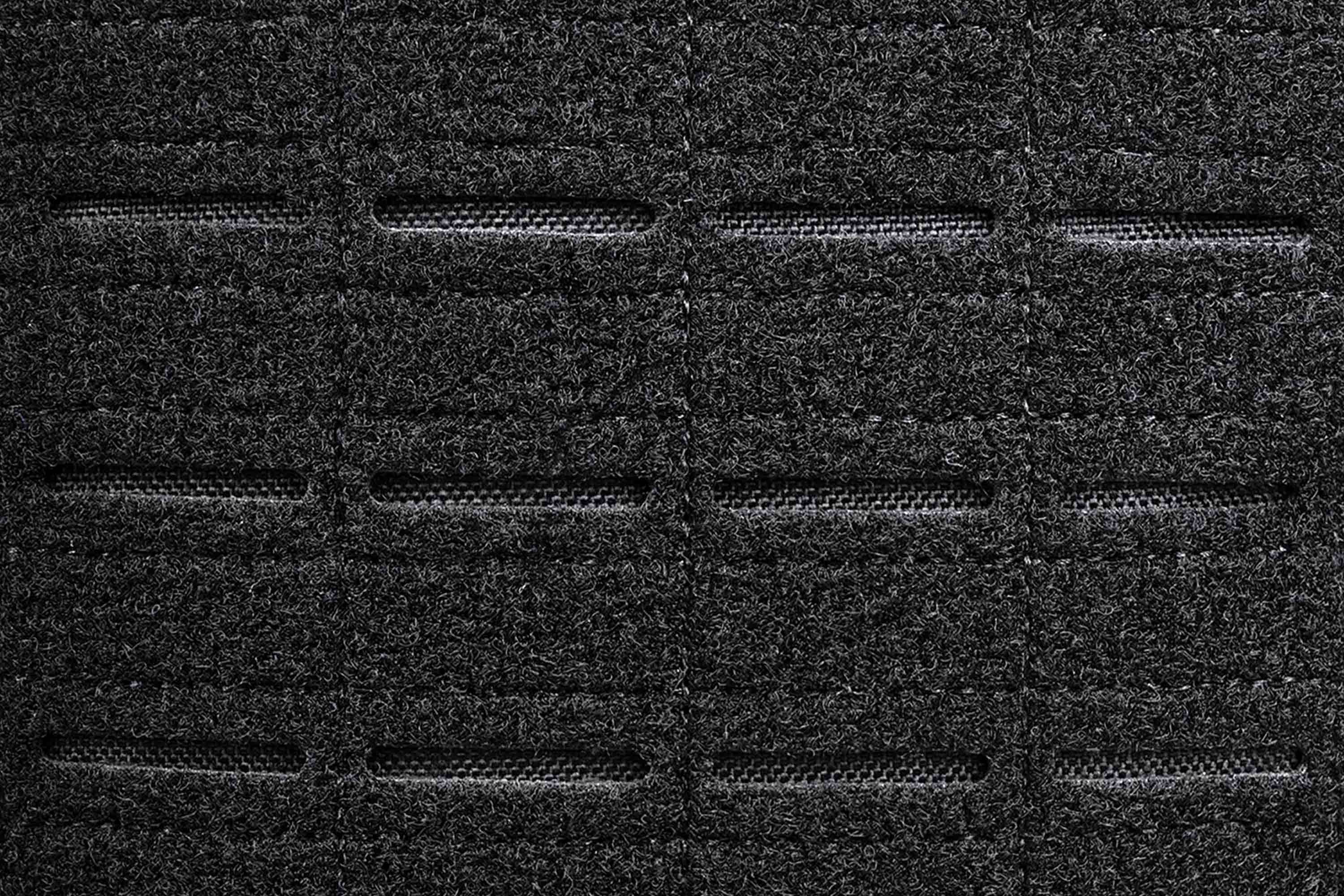 Nahaufnahme eines schwarzen taktischen MOLLE-Gurtstoffs mit lasergeschnittenen Schlitzen zur Befestigung modularer Ausrüstung und Zubehör.
