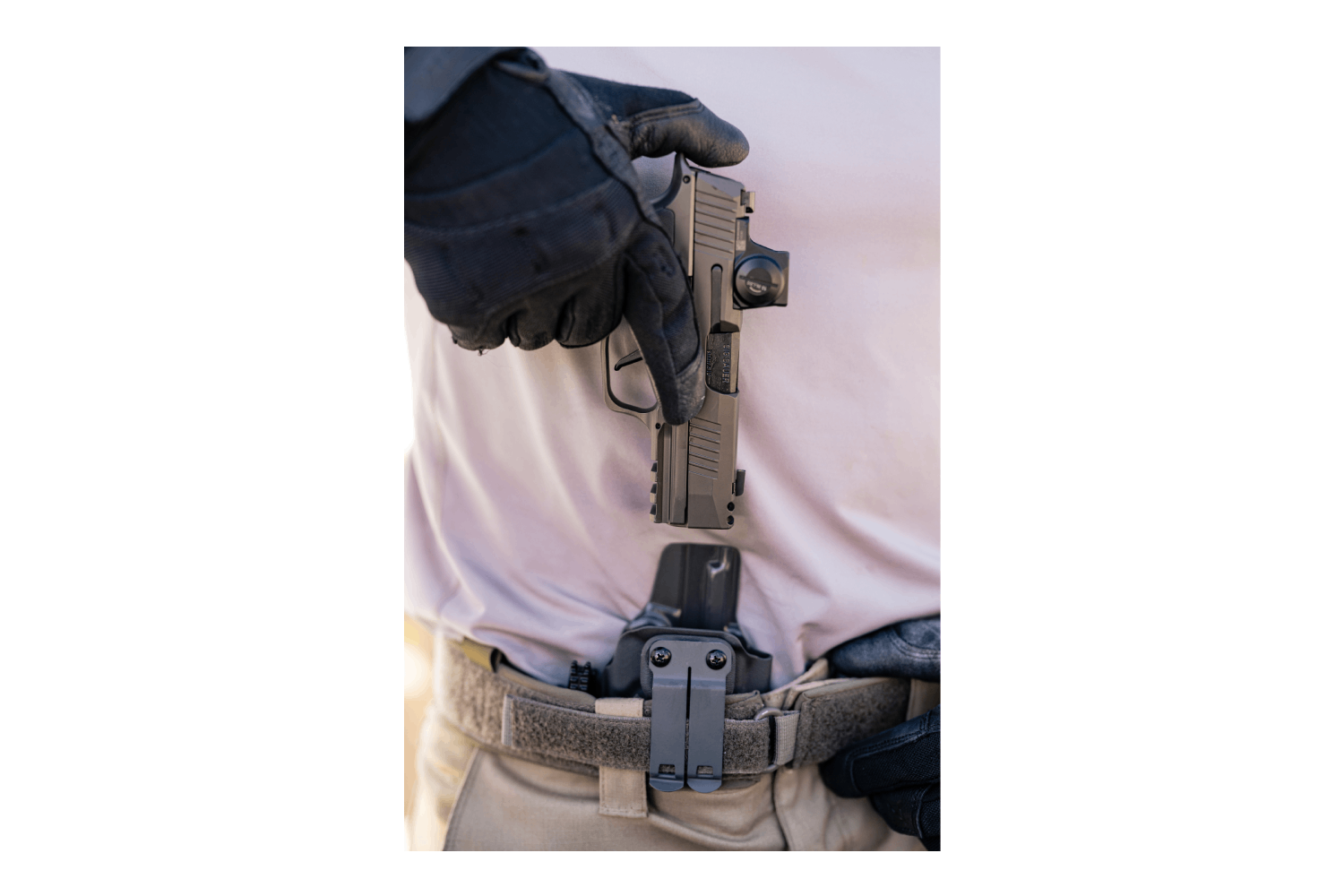 Person in taktischer Ausrüstung zieht eine schwarze Luftpistole aus einem Holster am Gürtel.