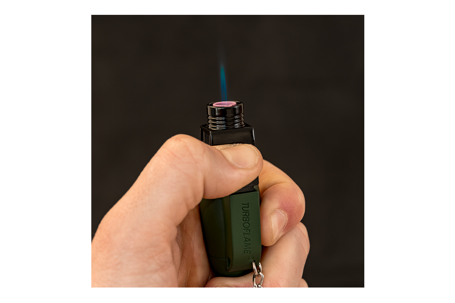 Hand hält ein Turbo Flame-Feuerzeug mit blauer Flamme, ideal für Outdoor-Aktivitäten und präzise Beleuchtung.