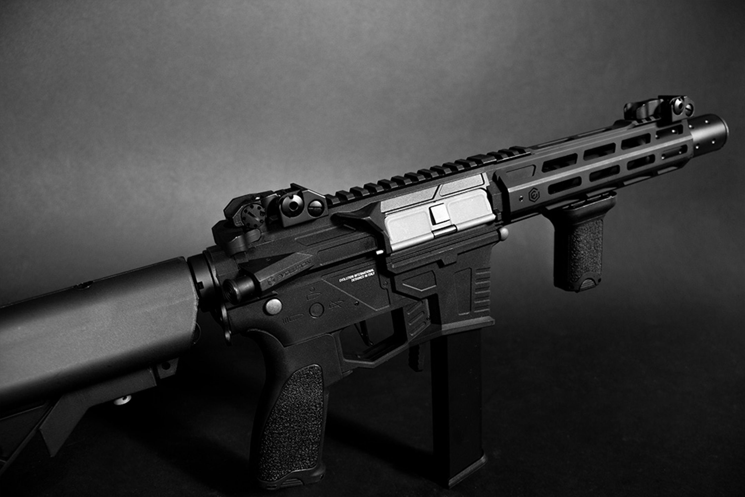 Schwarzes Evolution International-Luftgewehr mit M-LOK-Handschutz, taktischem Griff und eiserner Visierung auf dunklem Hintergrund.